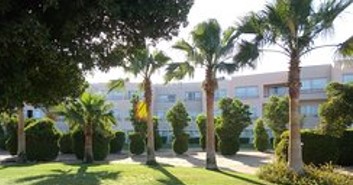 Garden facade with palms and trimmed hedges